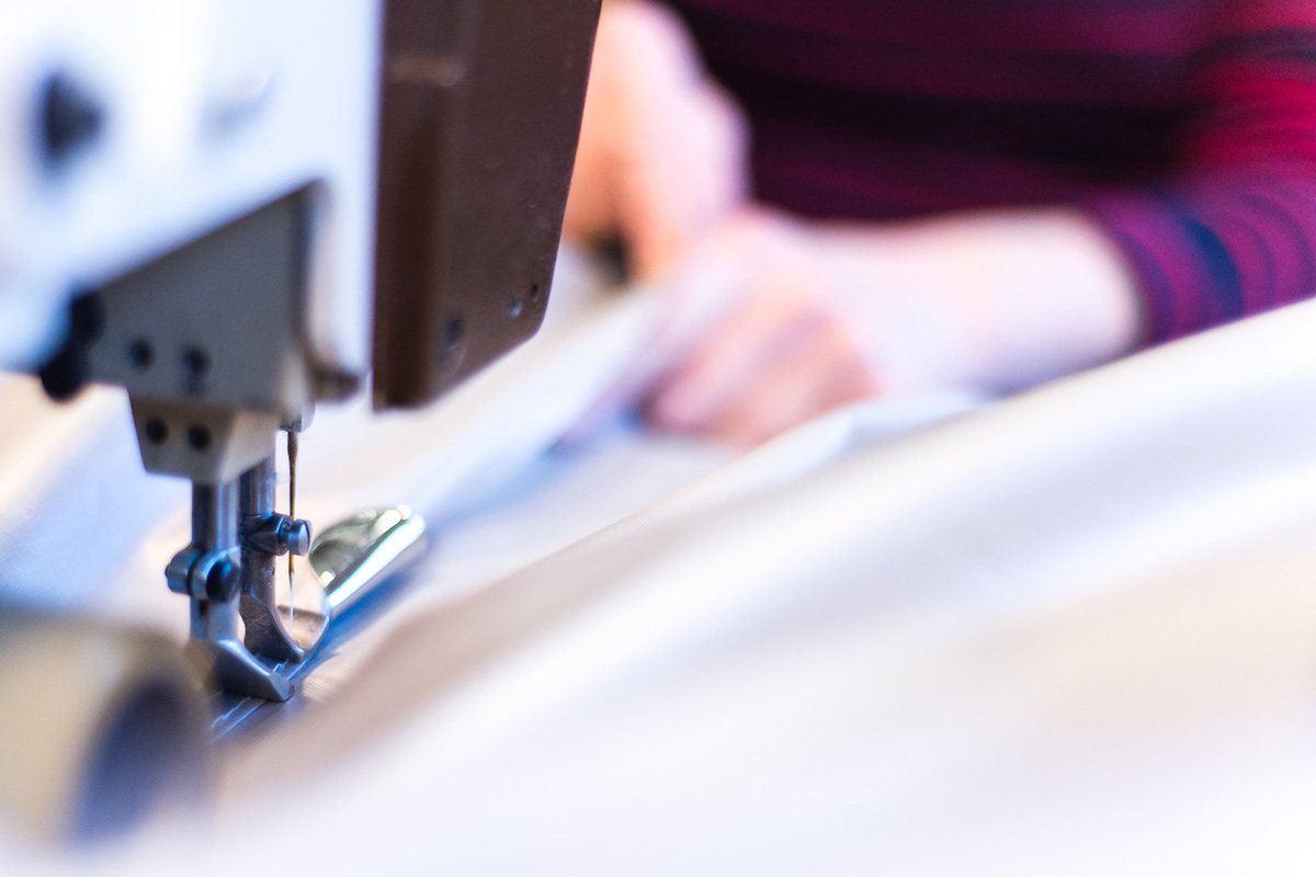 Operatör som syr i en duk vid en symaskin.